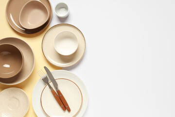 Set of clean plates, bowls and cutlery on color background