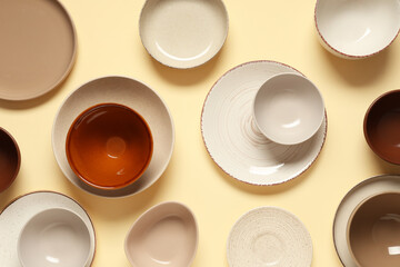 Set of clean plates and bowls on beige background