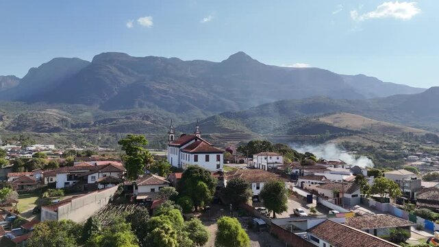 V&iacute;deo a&eacute;reo da Igreja Matriz de Nossa Senhora da Concei&ccedil;&atilde;o no centro hist&oacute;rico de Catas Altas, com a Serra do Cara&ccedil;a ao fundo, Minas Gerais, Brasil. 