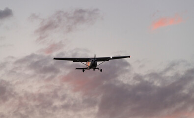 Small Plane Flying at Sunset with Vibrant Clouds