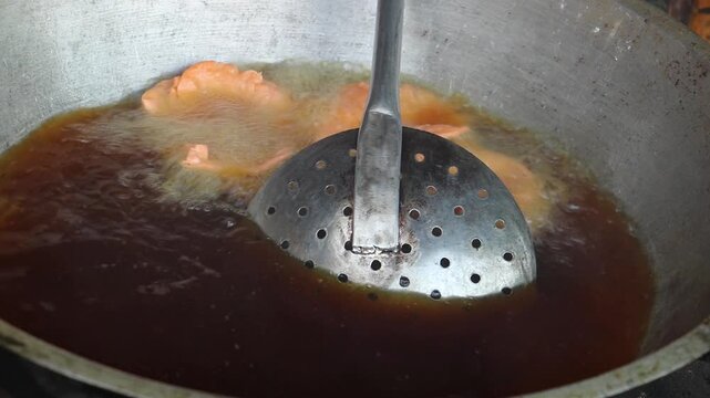 Snacks made of dough are fried in the hot oil of a kadai. Handmade crunchy salty snack food. 