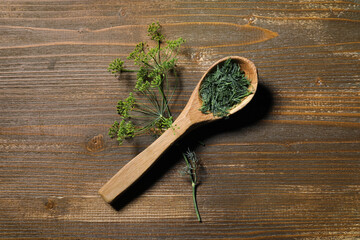 Spoon with fresh dill on wooden background, closeup
