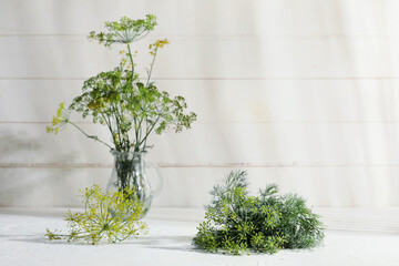 Glass jar with fresh dill on white wooden background