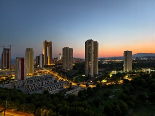 Obraz premium A twilight cityscape showcases modern skyscrapers with vibrant lights illuminating the sky