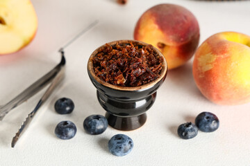 Hookah bowl of tobacco with berries, peaches and tongs on white background