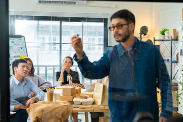 Corporate business team meeting discussion working plan in office room. Asian man employee writing on glass board presentation reusable Eco friendly product to colleague teamwork and project manager.