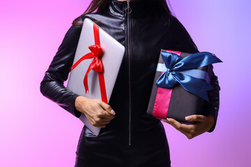 Young woman with gift and laptop on light background, closeup. Cyber Monday