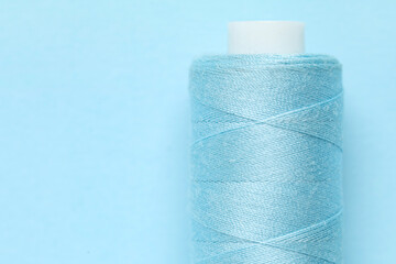 Spool of thread on blue background, closeup