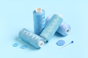 Spools of thread with ball pin and buttons on blue background