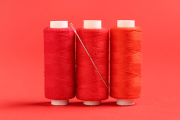 Spools of thread with needle on red background