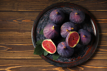 Plate with fresh ripe figs on brown wooden background, closeup