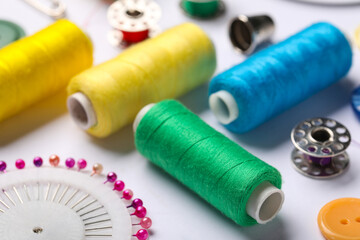 Composition with different thread spools and ball pins on white background, closeup