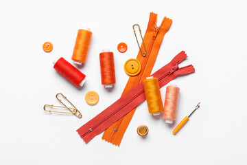 Composition with thread spools, zippers, pins and buttons on white background