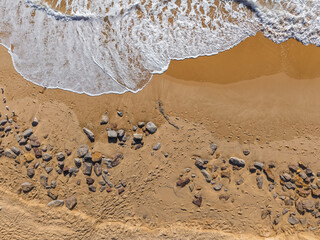 Aerial View of Ocean Waves Washing Over Sandy Beach with Rocks