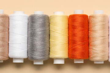 Set of different thread spools on beige background, closeup