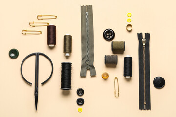 Composition with thread spools, zippers, pins and buttons on beige background
