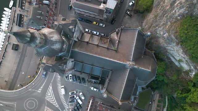 church dinant belgium town square traffic boats docked meuse river pedestrians walking reflecting vibrant to revealing from left right circling aerial shot collegiate 