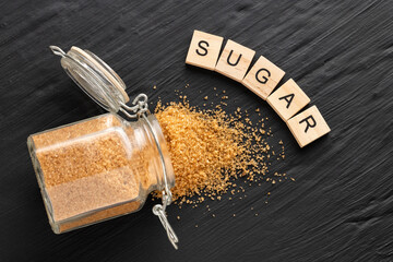 Brown sugar in a glass jar and spoon - Saccharum officinarum