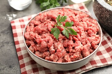 Raw minced meat with parsley and spices on grey table, closeup