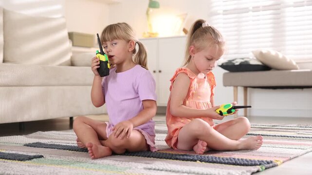 Little girls playing with walkie talkie toys at home