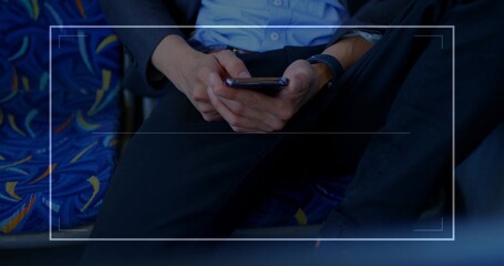 Checking smartphone male commuter wearing blazer and watch in train cabin with patterned upholstery