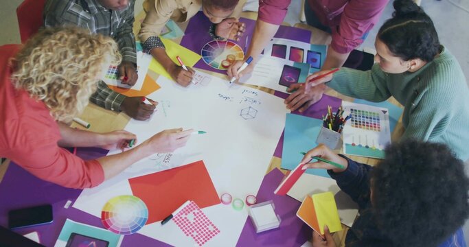 Creative team sketching layouts in meeting room, with color wheels and white drawing sheet