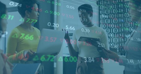 Discussing four women analyzing floating financial data overlay in office area, with laptops tablet