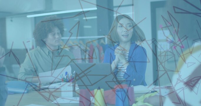 Reviewing sketches four designers collaborating around desk in studio, with glass board and laptop - Powered by Adobe