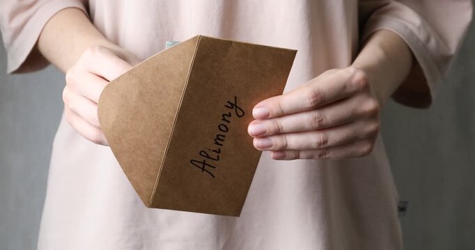 Alimony. Woman taking money from envelope on blurred background, closeup