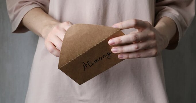 Alimony. Woman taking money from envelope on blurred background, closeup