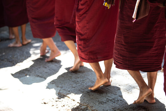 The Path of Devotion: Barefoot Buddhist Monks in Traditional Saffron Robes Collecting Alms in Mandalay, Myanmar