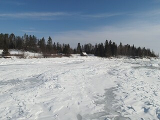 Fototapeta premium Aerial view of massive icebergs along Lake Superior’s shores on a sunny winter day, highlighting frozen formations, sparkling ice, and a vast winter landscape. 