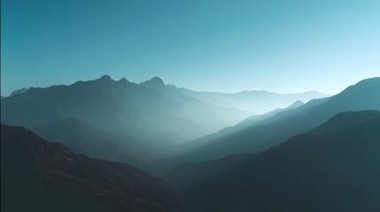Fototapeta premium Jagged mountain peaks emerge through atmospheric mist under a clear blue sky.