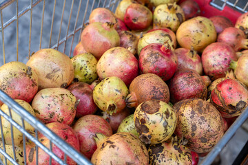 A collection of ripe pomegranates in a metal cart, showcasing vibrant colors and textures, perfect for market displays or agricultural themes.