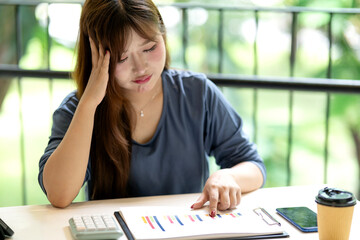 Asian adult woman business professional analyzing financial data reports feeling stress work pressure problem solving office cafe home