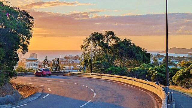 A winding road descends from Ouen Toro, Noum&eacute;a, New Caledonia, at sunset.