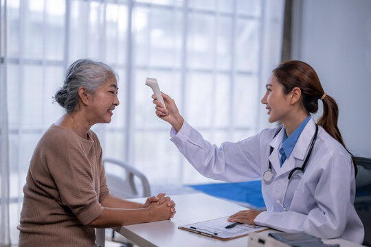 Doctor checking senior patient temperature with infrared thermometer - Powered by Adobe