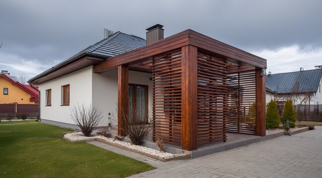 Modern house with wooden pergola and manicured lawn under cloudy sky.