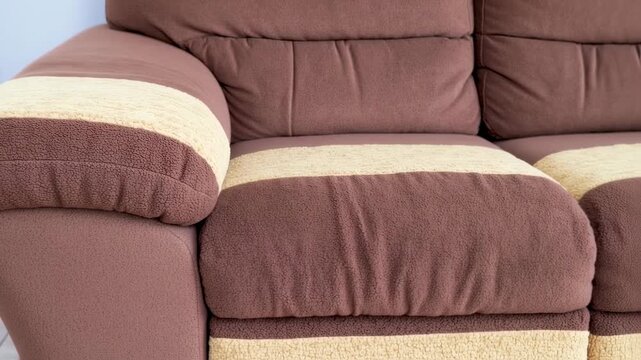 Close-up of a brown sofa with cream-colored stripes on the armrests and seat cushions