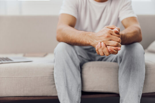 Pensive man sitting on a couch, reflecting on life. Casual attire, natural light creating a calming atmosphere. Perfect for modern lifestyle themes. - Powered by Adobe