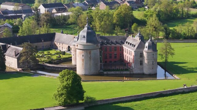 castle lavaux sainte anne or ch&acirc;teau de old building green fields water body town background gardens red walls to left around right close pans aerial drone 
