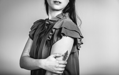 Fashion black and white portrait of a beautiful brunette woman smiling in a styling outfit on light gray studio background