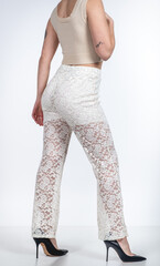 Elegant mid-body fashion portrait of brunette model in lace outfit and high heels on white background