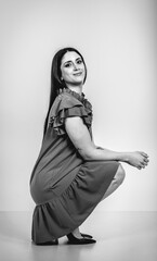 Fashion black and white portrait of a beautiful brunette woman smiling in a styling outfit on light gray studio background