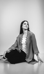 Fashion black and white portrait of a beautiful brunette woman smiling in a styling outfit on light gray studio background