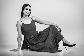 Fashion black and white portrait of a beautiful brunette woman smiling in a styling outfit on light gray studio background