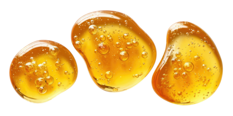 Three golden honey drops or cosmetic pearls glowing with rich amber hues and bubbles