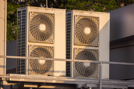 Rooftop HVAC units and ventilation systems under warm sunset light, industrial cooling and air conditioning equipment outdoors