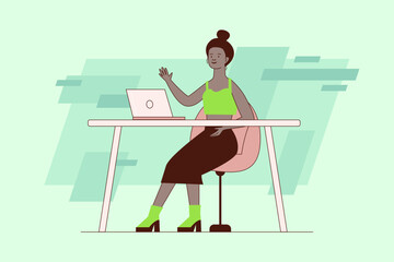 Woman wearing green top and black skirt sitting at her desk, smiling and waving. Woman engaged in video call using her laptop on green background