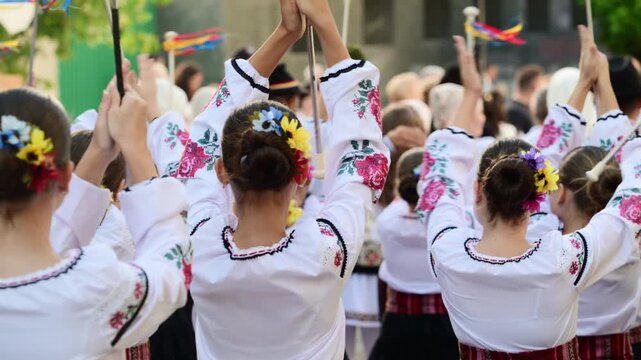 A group of dancers wearing embroidered garments joyfully performs traditional folk dance at a vibrant cultural festival outdoor